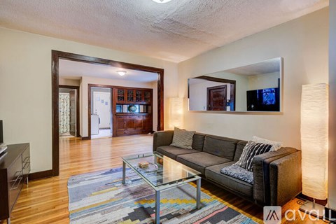 A living room with a grey couch and a glass coffee table.