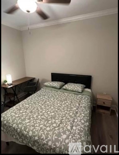 A bedroom with a bed, nightstand, and a ceiling fan.