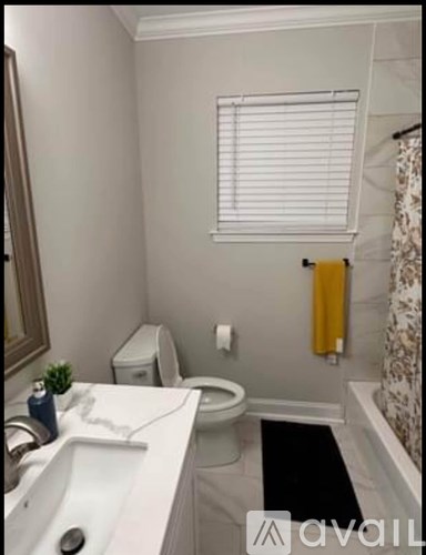 A bathroom with a toilet, sink, and a window with blinds.