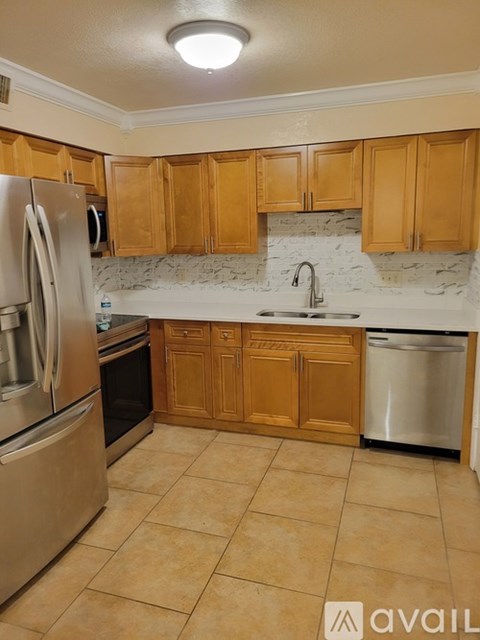 A kitchen with wooden cabinets and a marble backsplash.