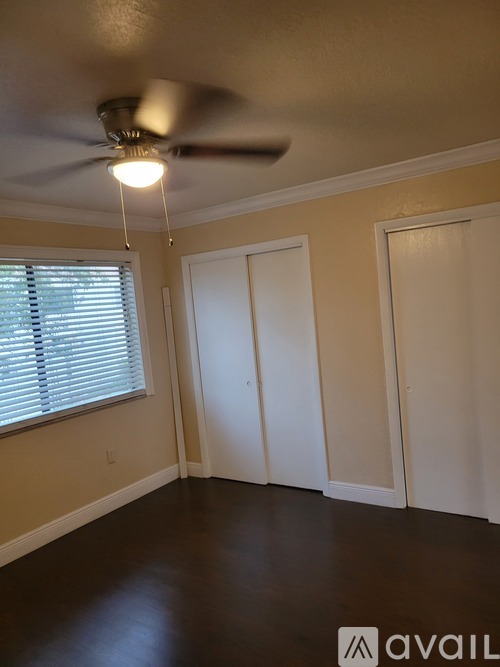 A room with a ceiling fan and a window with blinds.