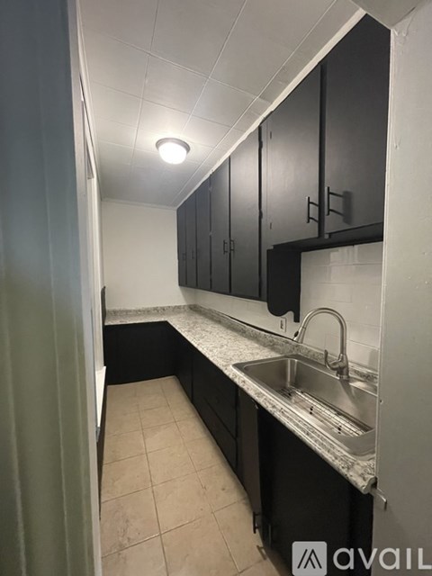 A kitchen with black cabinets and a stainless steel sink.
