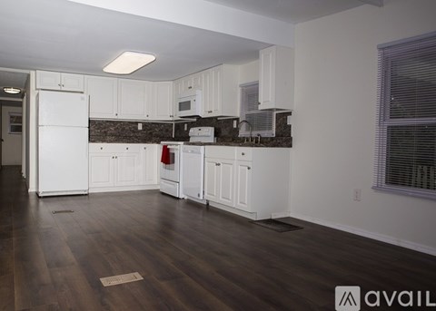 A kitchen with white cabinets and a wooden floor.