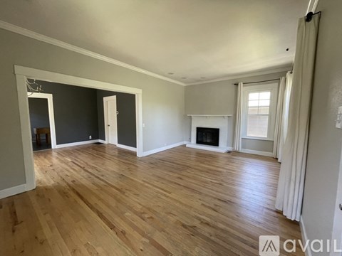 A spacious room with wooden flooring and a fireplace.