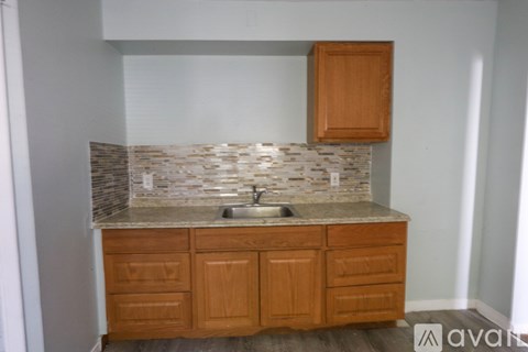 A kitchen with wooden cabinets and a stone backsplash.