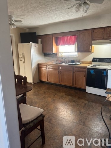 A kitchen with brown cabinets and a white fridge.