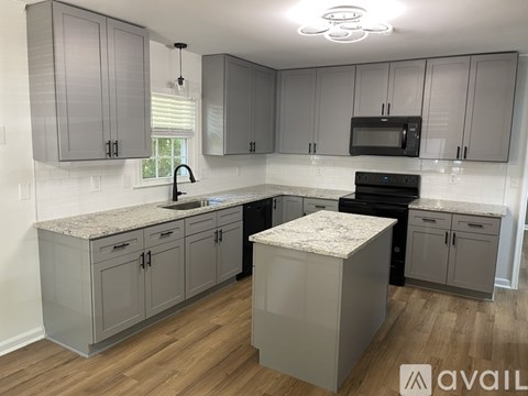 A kitchen with grey cabinets and a granite countertop.