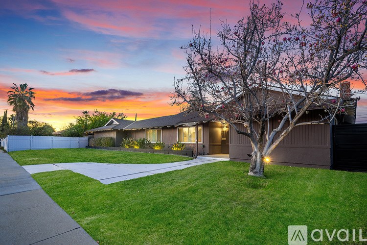 A house with a tree in front of it and a sunset in the background.