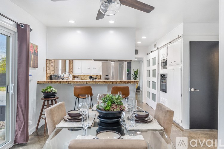 A modern dining room with a table set for two and a ceiling fan.