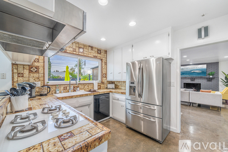 A modern kitchen with a stainless steel refrigerator and a backsplash made of stone tiles.