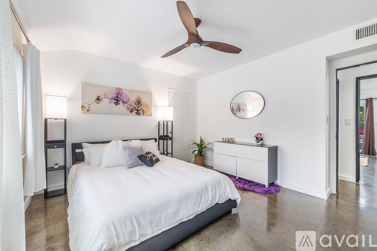 A bedroom with a large bed and a ceiling fan.