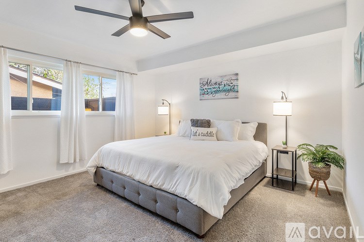 A bedroom with a large bed, a ceiling fan, and a plant.