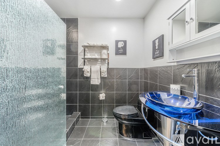 A modern bathroom with a glass shower and a round sink.