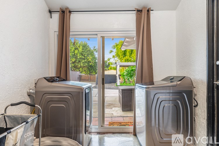 A room with two microwaves and a window with curtains.