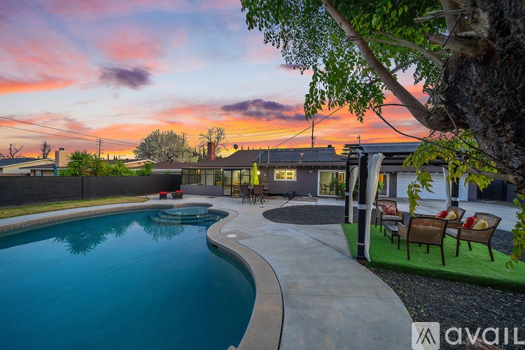 A pool with a sunset in the background and chairs around it.