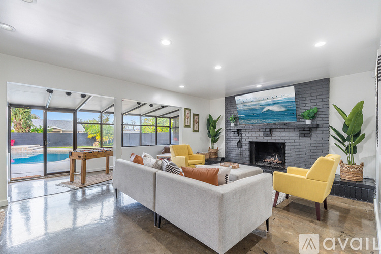 A living room with a grey couch, yellow chair, and a fireplace.