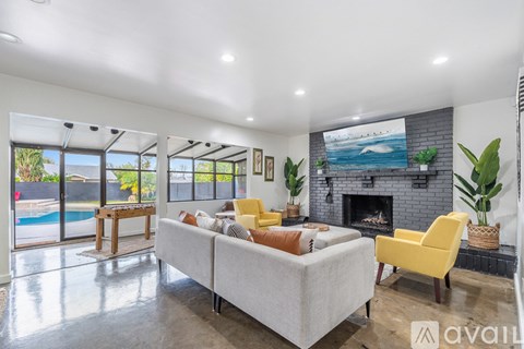 A living room with a grey couch, yellow chair, and a fireplace.