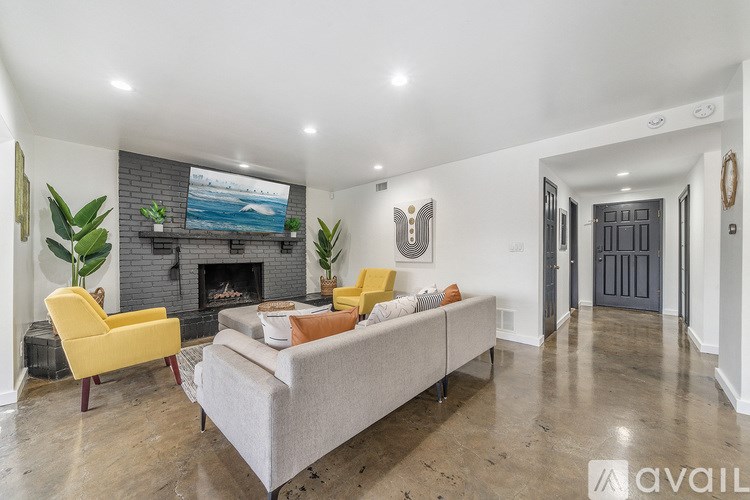 A living room with a grey couch, yellow chairs, and a fireplace.