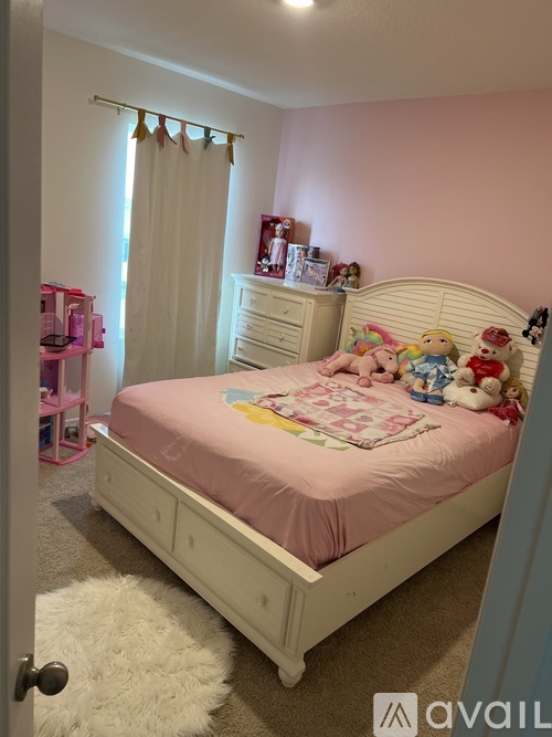 A child's bedroom with a pink bed and a white rug.