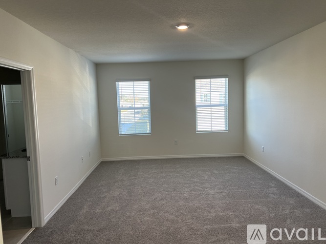 A spacious room with carpeted floor and two windows.