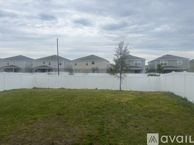 A grassy area in front of a row of houses with a white fence.