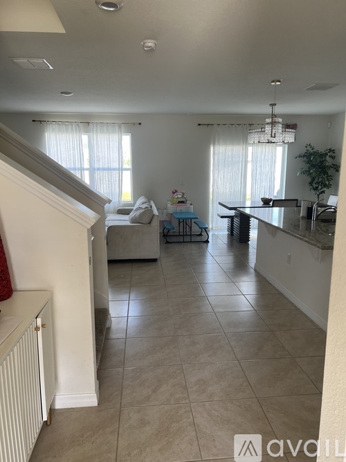 A living room with a couch, a dining table, and a kitchen area.