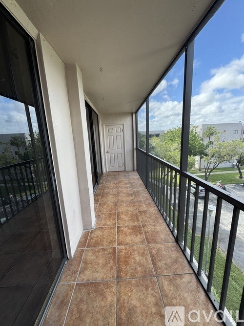 A balcony with a black railing and brown tile floor.