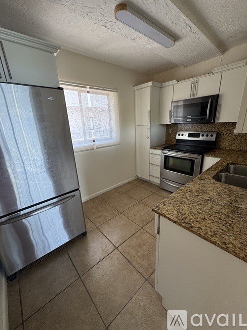 A kitchen with a refrigerator, microwave, oven, and sink.
