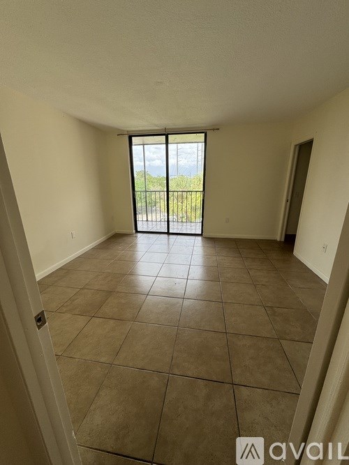 A room with tiled flooring and a view of a parking lot through a sliding glass door.