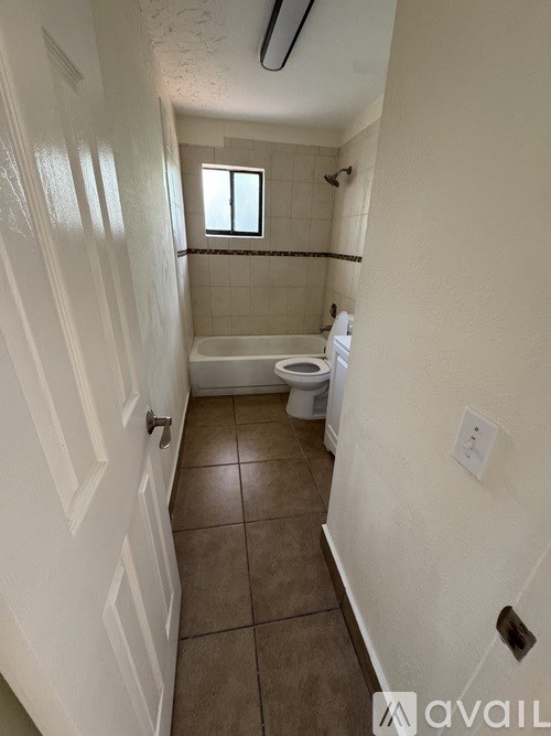 A bathroom with a toilet, tub, and window.