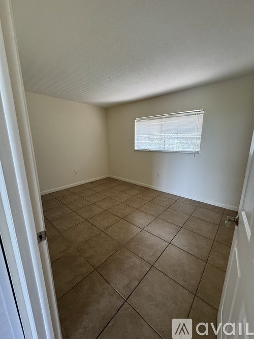 A room with a tiled floor and a window with blinds.