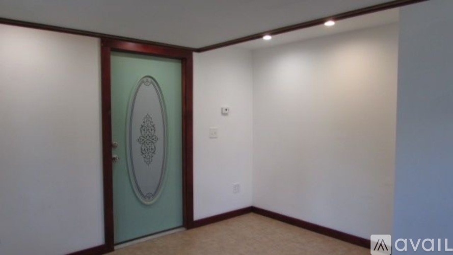 A room with a green door and a light switch on the wall.