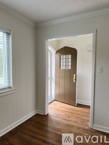 A room with a wooden floor and a door with a window on the side.
