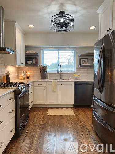 A modern kitchen with wooden floors and stainless steel appliances.