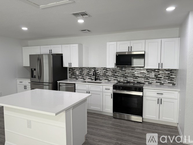A kitchen with white cabinets and a black refrigerator.