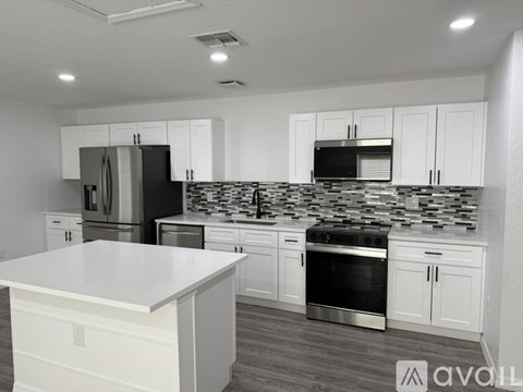 A kitchen with white cabinets and a black refrigerator.