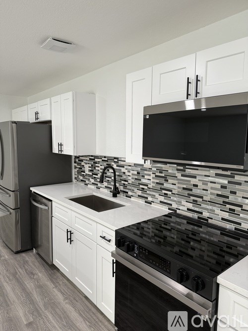 A modern kitchen with black appliances and white cabinets.