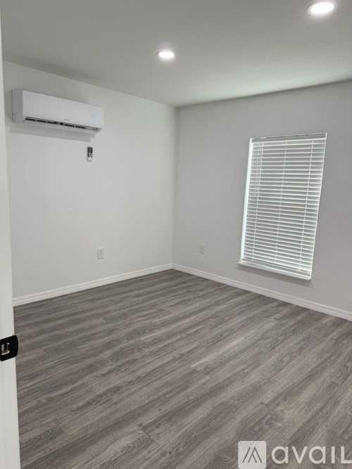 A room with a window covered by blinds and a wall-mounted air conditioner.