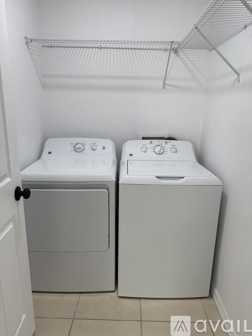 Two white front loading washing machines in a small laundry room.