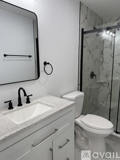 A bathroom with a toilet, sink, mirror, and shower.