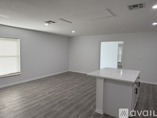 A spacious room with a white counter and wooden flooring.