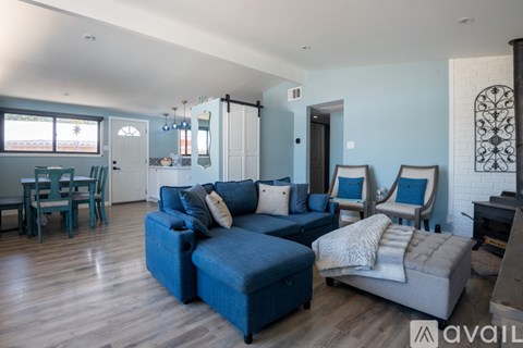 A living room with a blue couch and a white chair.