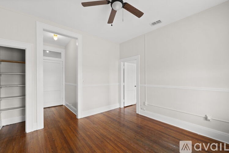 A room with a ceiling fan and wooden floors.