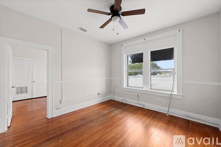 A room with a ceiling fan and a window overlooking a street.