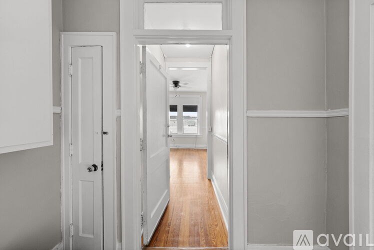 A hallway with a wooden floor and white walls.