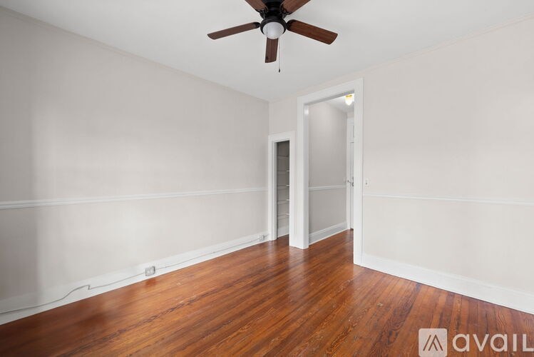 A room with a ceiling fan and wooden floors.