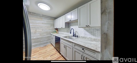 A kitchen with wooden floors and white cabinets.