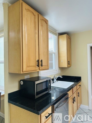 A kitchen with wooden cabinets and black countertops.