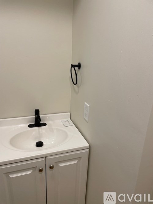 A white sink with a black faucet and a black soap dish.