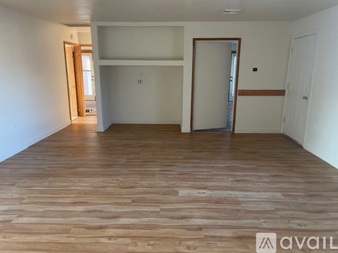 A room with wooden flooring and white walls.